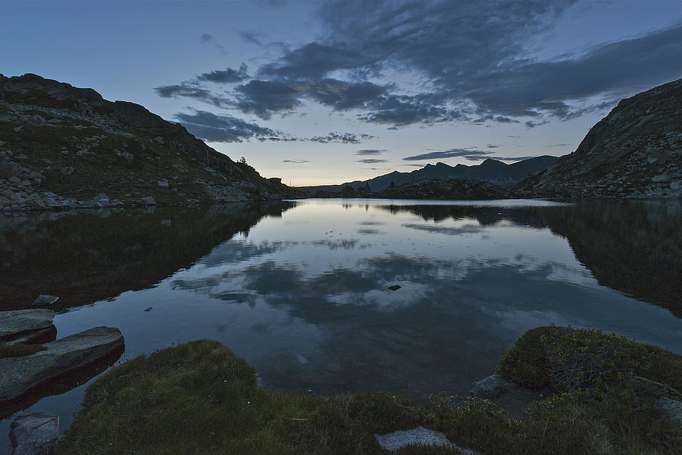 body of water surrounding rocky mountains during night time HD wallpaper