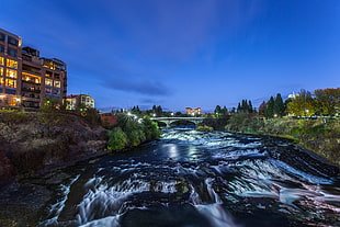 HD Photography of running stream beside high rise building under blue sky during daytime, spokane river HD wallpaper