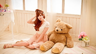 woman in white cap sleeved dress sitting beside brown bear plush toy
