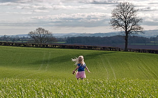 girl in blue shirt standing on green grass field HD wallpaper