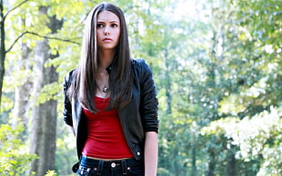woman wearing black zip-up jacket with red scoop-neck shirt in a forest during day time