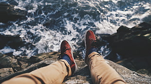 pair of brown-and-white low-top sneakers, legs, sea, waves, blurred