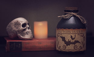 close up photo on bottle with cork lid and skull on book