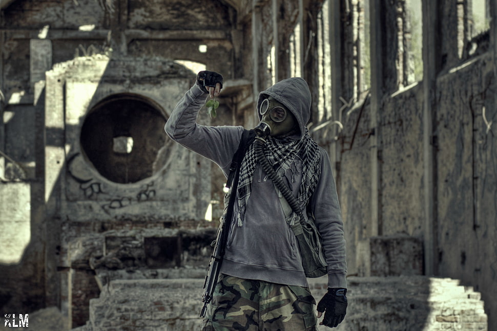 soldier wearing gas mask with rifle beside grey concrete wall HD wallpaper