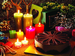 photography of round chocolate cake beside pillar candles