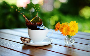 white ceramic coffee cup near yellow flowers