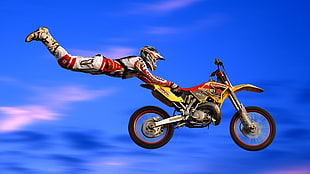 Man performing stunt with yellow and red motocross dirt bike