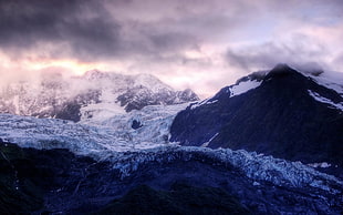mountain coated by ice under stormy cloud