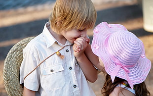 boy in white sports shirt holding hands to girl in pink hat