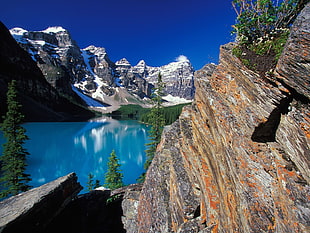 blue lake surrounded by rocky mountain under clear blue sky HD wallpaper