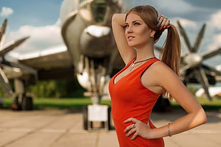 woman wearing tank top holding her hair in front of airplane