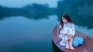 woman in white robe on brown boat raft on top of body of water