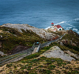 high angle photo of white and red house near lighthouse on top of rock mountain beside sea, point reyes lighthouse
