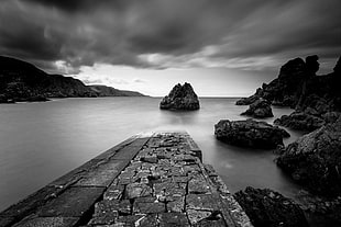 black and white photo of body of water surrounded by rock formation, scotland