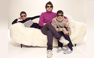 photo of three men in sweaters sitting on sofa