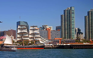 sailship on the sea near high rise buildings HD wallpaper