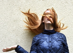 woman wearing blue leather jacket against concrete wall