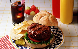 hamburger on top of ceramic plate beside drinking glass