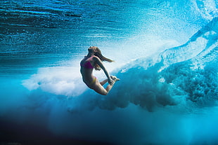 underwater photography of woman wearing red bikini under wave