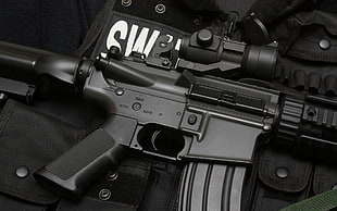 black rifle with scope and Swat vest