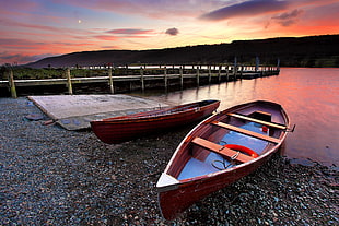 two brown wooden rowboats docked on lake