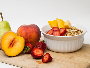 fruits near a white ceramic bowl on top of chopping board