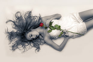 woman wearing strapless dress holding red rose lying on surface