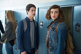girl wearing blue denim button-up jacket beside locker and boy in blue dress shirt and grey crew-neck shirt