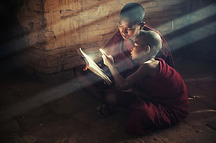 monks in red suit reading book