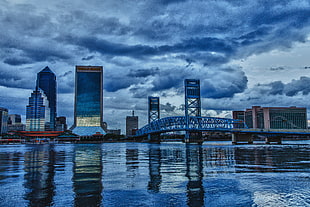 high-rise building across body of water under cloudy skies