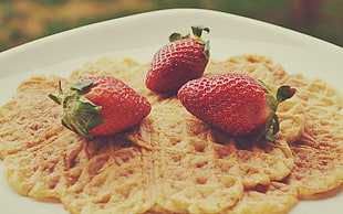 three strawberries on top of waffles