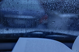 book beside windshield with water dew