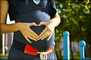 pregnant woman showing heart hand figure on her baby bump