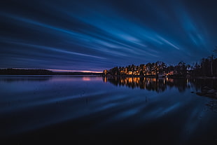 landscape photography of body of water beside lighted town