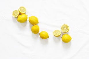five lemons and two sliced lemons on white textile