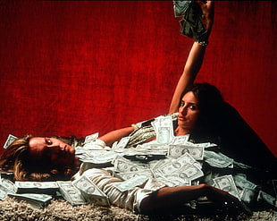 woman and man lying on fleece textile while covered with US dollar bills
