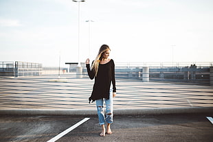 standing woman in brown long-sleeved shirt and blue distressed jeans