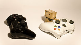 black Sony PS3 controller and white Xbox 360 controller with carton robot