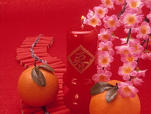 closeup photo of two Orange fruits and red Kanji candle