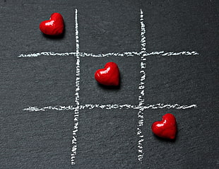 three plastic hearts placed on tic-tac-toe drawing