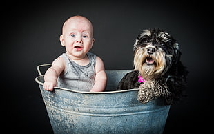 child with black dog on gray galvanized bucket