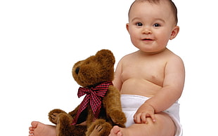 toddler boy with white diaper near brown teddy bear