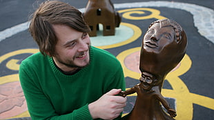 man in green sweater holding statuette