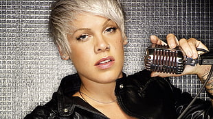woman wears black zip-up jacket holds silver microphone