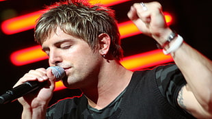 man holding microphone raising left hand