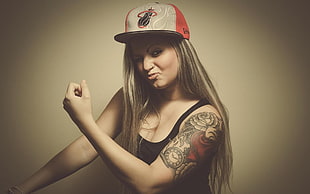 woman in black tank top and Miami Heat cap showing tattoo