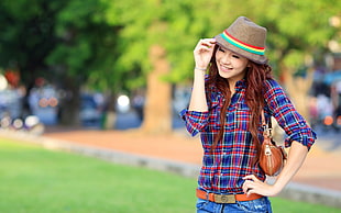 selective focus of woman wearing plaid shirt and holding brown cap