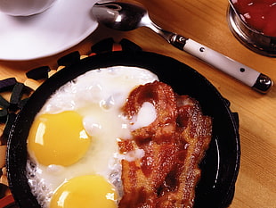 cooked bacon and egg on a black frying pan