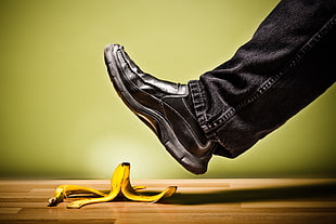 person in black jeans and black loafers over peel of yellow banana