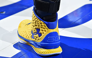 person wearing yellow and blue Under Armour 3C shoe